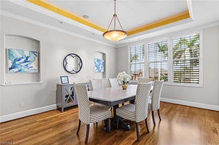 Dining space featuring a tray ceiling, crown molding, and light wood-type flooring