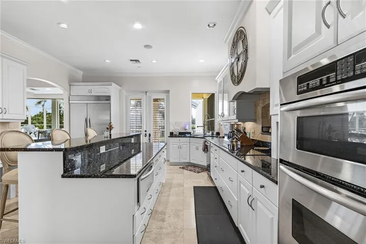 Kitchen featuring stainless steel appliances, a breakfast bar area, ornamental molding, white cabinetry, and dark stone counters