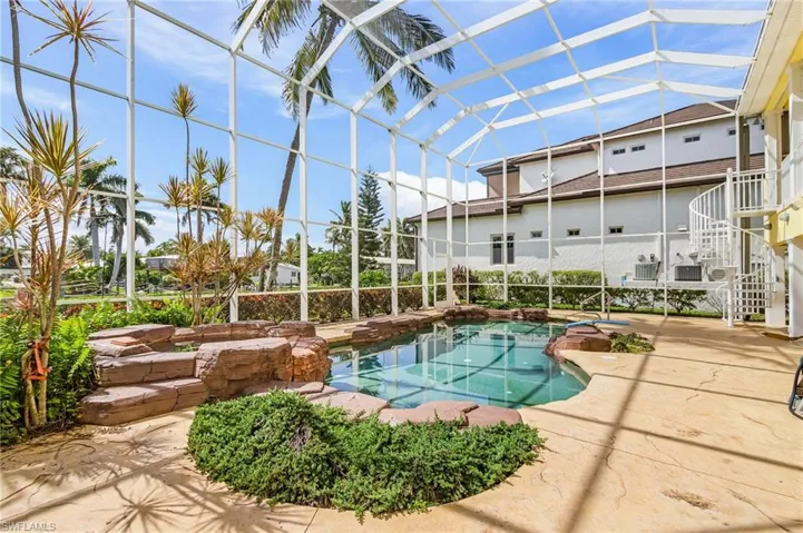 Swimming pool featuring a jacuzzi, a sunroom, a lanai, a patio, and stairway