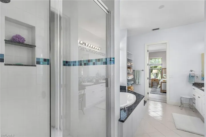 Full bathroom featuring vanity, a stall shower, ensuite bathroom, a garden tub, and light tile patterned floors