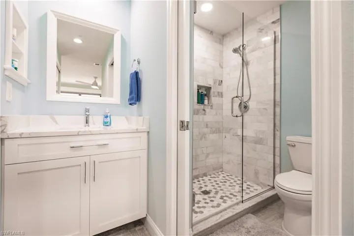 Bathroom featuring an enclosed shower, toilet, and vanity