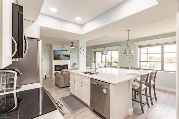 Kitchen with white cabinetry, sink, ceiling fan, a kitchen island with sink, and stainless steel dishwasher