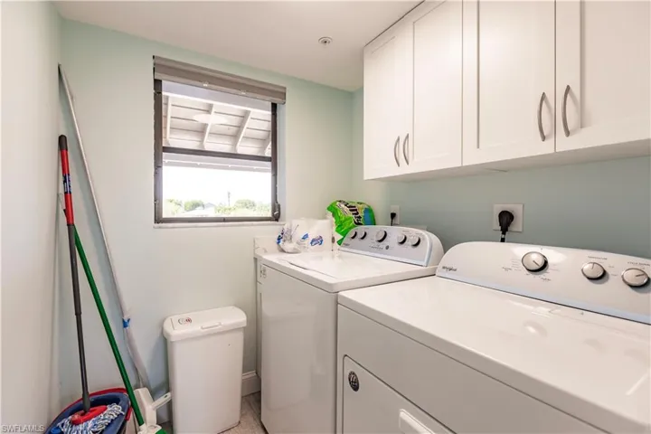 Clothes washing area featuring cabinets and separate washer and dryer