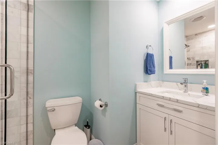 Bathroom featuring a shower with shower door, toilet, and vanity