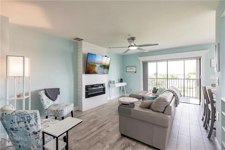 Living room with light hardwood / wood-style floors, ceiling fan, and a large fireplace