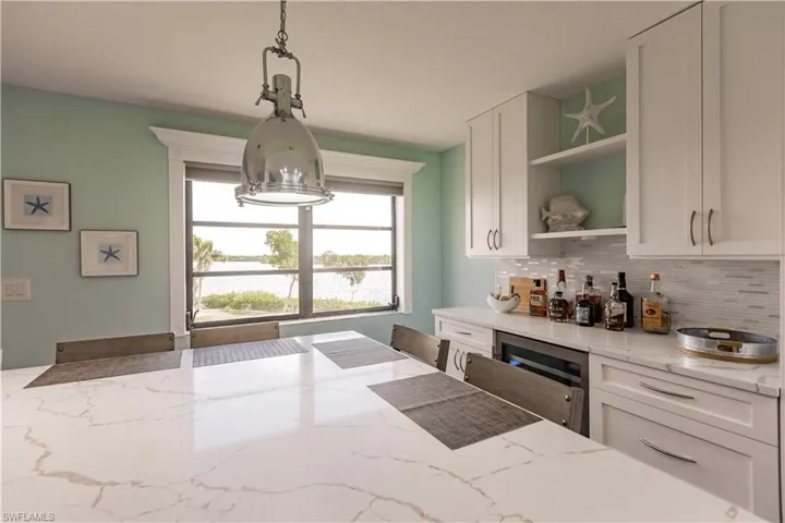 Kitchen featuring pendant lighting, white cabinetry, and light stone countertops