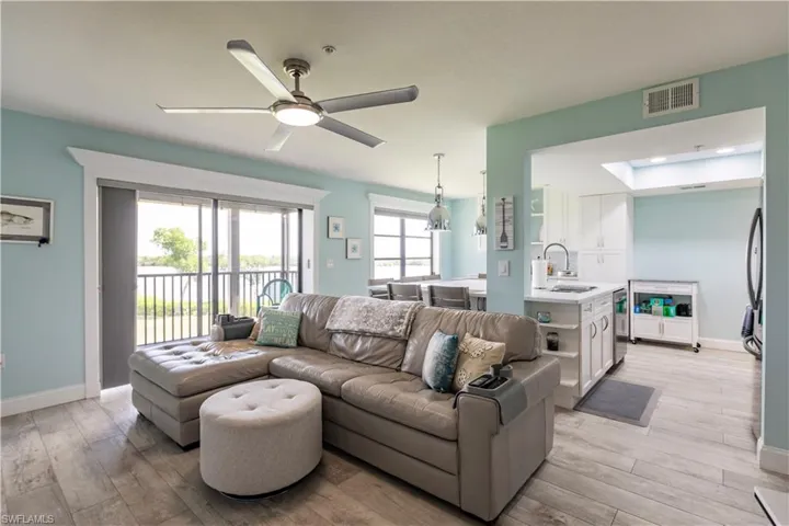 Living room featuring light wood-type flooring, ceiling fan, and sink