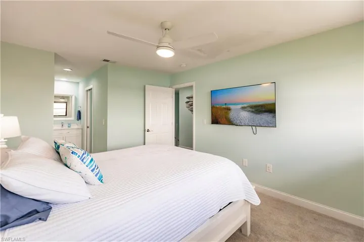 Bedroom featuring ensuite bath, sink, light carpet, and ceiling fan