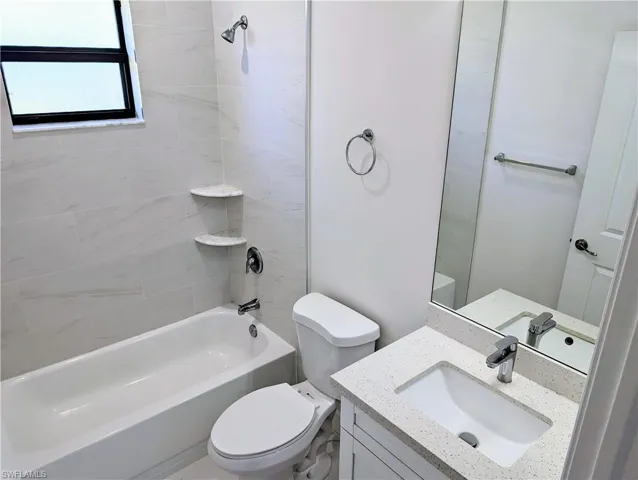 Full bathroom featuring tiled shower / bath combo, toilet, and vanity