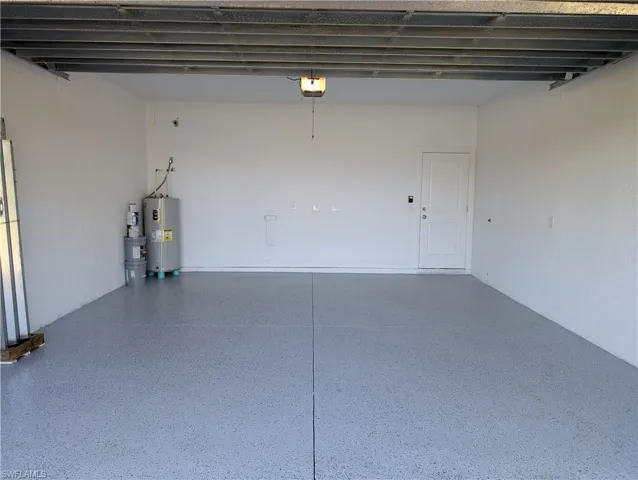 Garage featuring electric water heater and a garage door opener