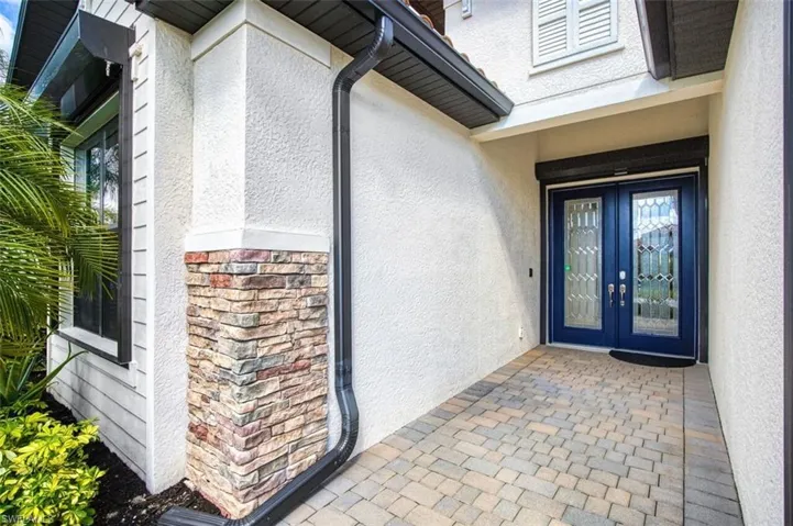 Entrance to property featuring stucco siding, stone siding, and french doors