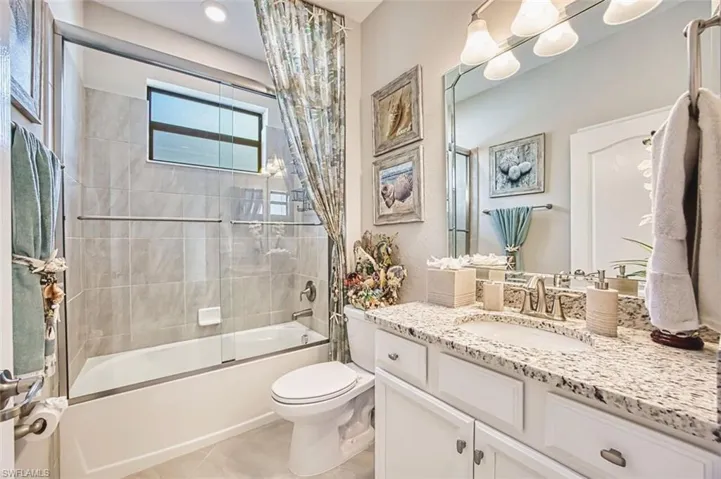 Full bath with vanity, shower / bath combination with glass door, and light tile patterned floors