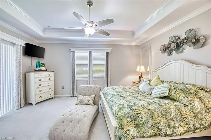 Bedroom with carpet flooring, ceiling fan, crown molding, and a tray ceiling