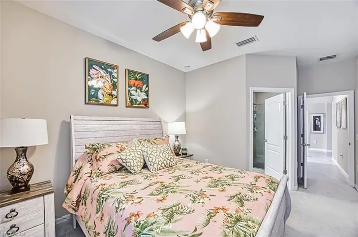 Carpeted bedroom featuring ensuite bath and a ceiling fan