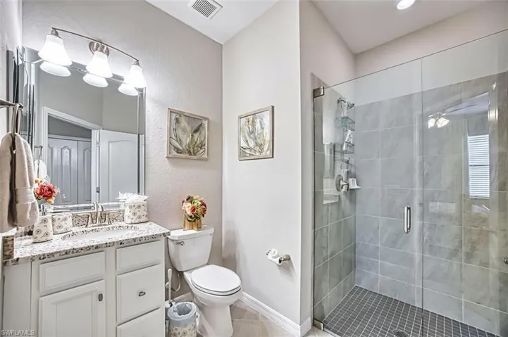 Ensuite -Full bath featuring vanity, a shower with glass enclosure, a textured wall, and light tile patterned floors