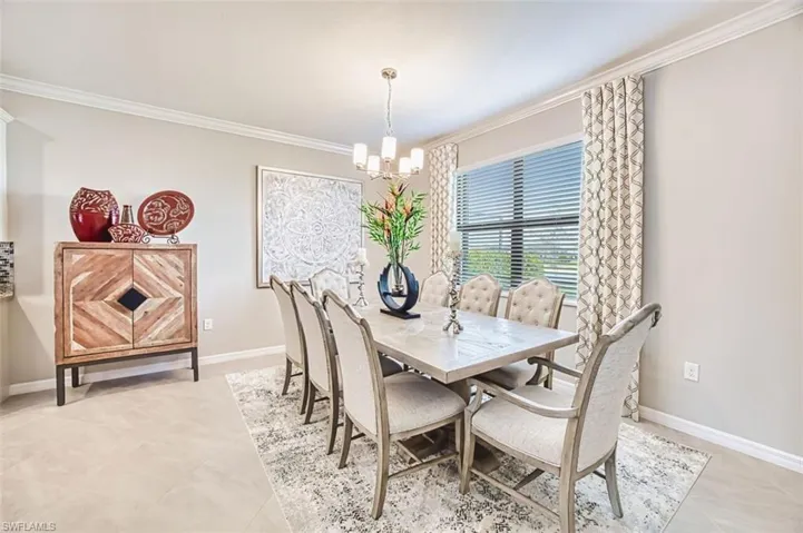 Dining space with crown molding, a chandelier, and light tile patterned flooring