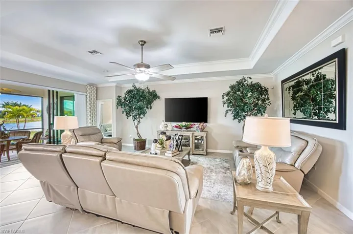 Living area featuring a ceiling fan, a tray ceiling, and crown molding