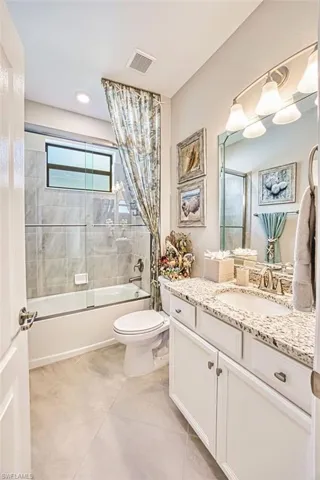 Bathroom featuring vanity, enclosed tub / shower combo, and light tile patterned floors