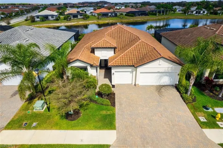 View of front of house with an attached 3 car garage, stucco siding, a tile roof, a residential view, and a water view