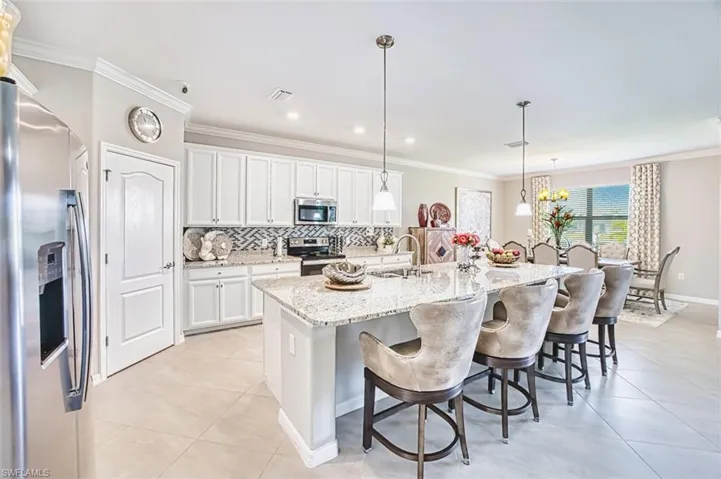 Kitchen featuring stainless steel appliances, crown molding, white cabinets, a breakfast bar area, and granite countertops