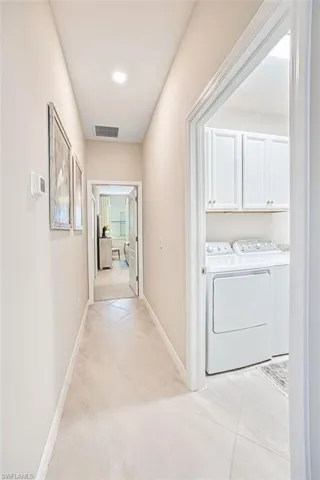 Corridor with washing machine and clothes dryer, light tile patterned floors, and recessed lighting