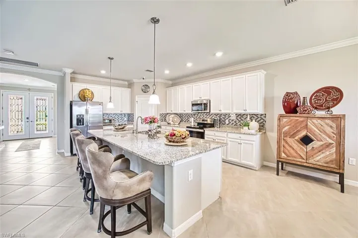 Kitchen with crown molding, a kitchen breakfast bar, and white cabinets tile back splash