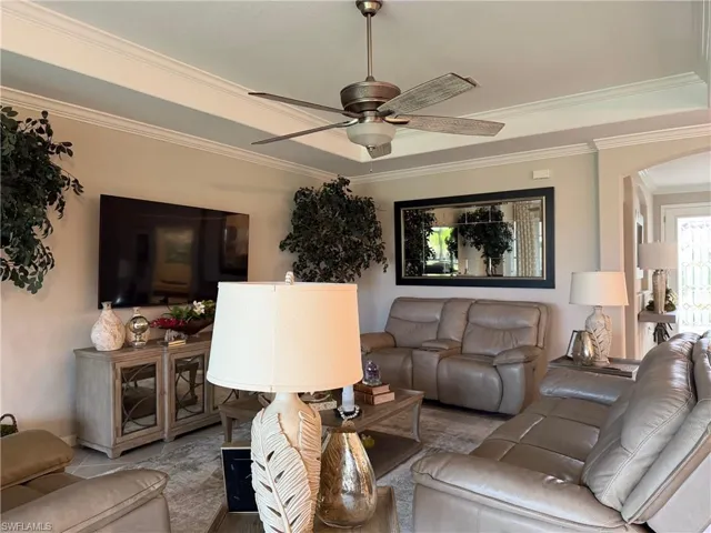 Living room with ceiling fan, arched walkways, and crown molding