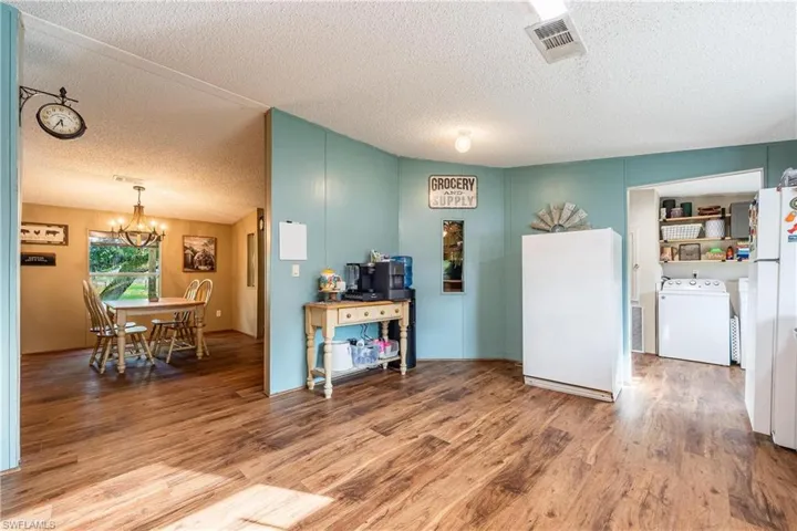 Kitchen featuring wood-type flooring, washer / clothes dryer, a textured ceiling, a chandelier, and white fridge