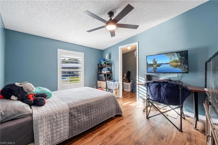 Bedroom with ceiling fan, hardwood / wood-style flooring, lofted ceiling, and a textured ceiling
