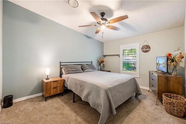 Bedroom with a textured ceiling, ceiling fan, and light colored carpet