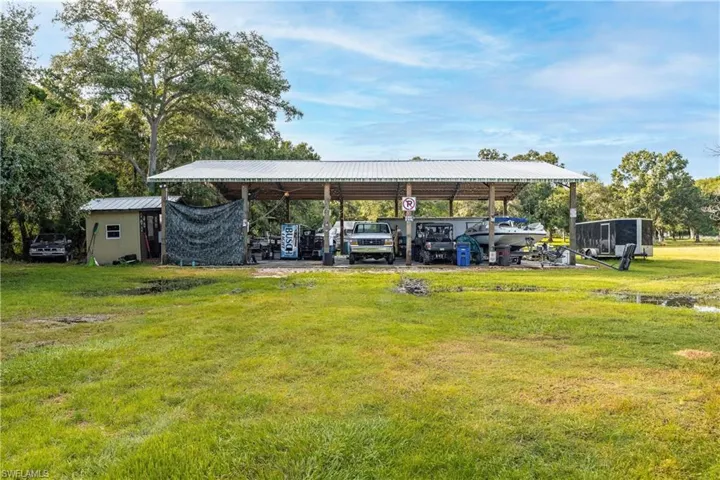 View of parking with a lawn and a carport