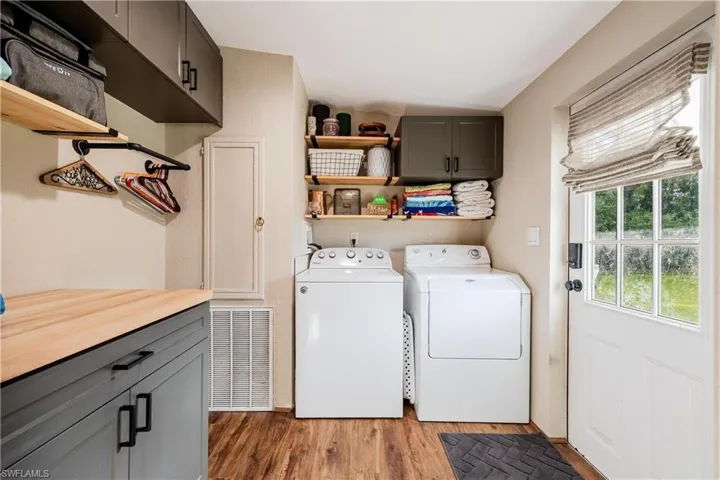 Clothes washing area featuring cabinets, light hardwood / wood-style floors, and washing machine and clothes dryer