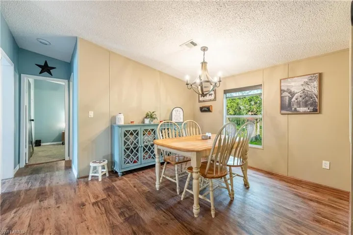Dining space with vaulted ceiling, a textured ceiling, dark hardwood / wood-style floors, and a chandelier