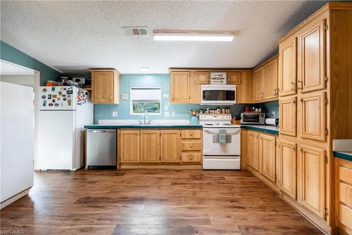 Kitchen featuring sink, appliances with stainless steel finishes, hardwood / wood-style floors, and a textured ceiling