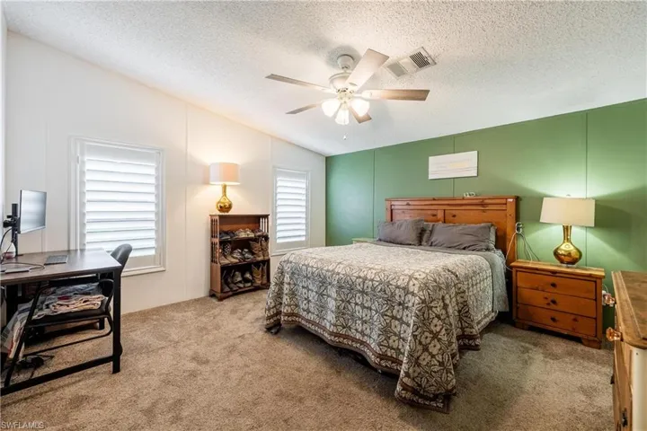 Bedroom with multiple windows, vaulted ceiling, light carpet, and ceiling fan