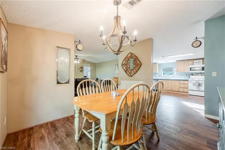 Dining space with a textured ceiling, ceiling fan with notable chandelier, and hardwood / wood-style flooring