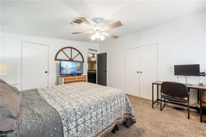 Carpeted bedroom featuring a textured ceiling and ceiling fan