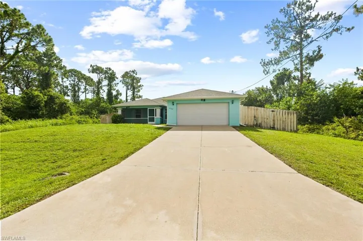View of front facade featuring driveway, a garage, and stucco siding