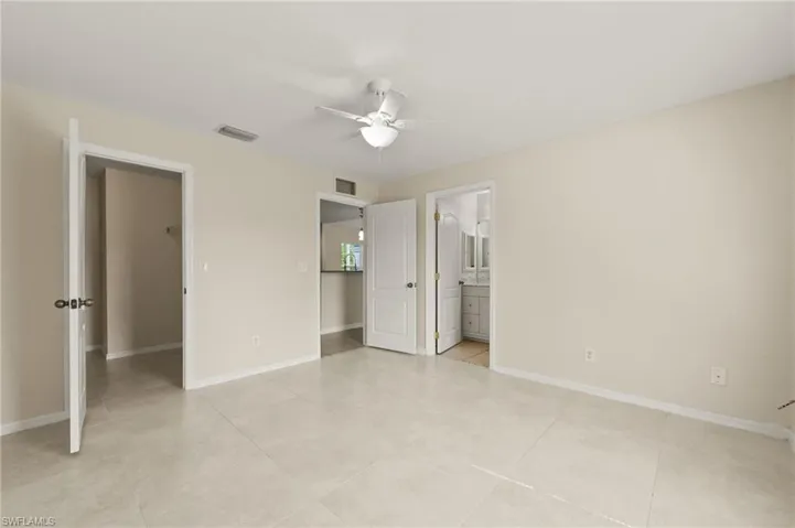 Unfurnished bedroom featuring light tile patterned flooring, connected bathroom, and ceiling fan