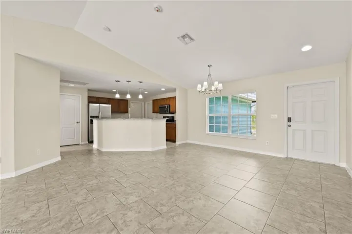 Unfurnished living room featuring a chandelier, lofted ceiling, and recessed lighting