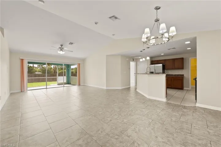 Unfurnished living room featuring lofted ceiling, a chandelier, and ceiling fan