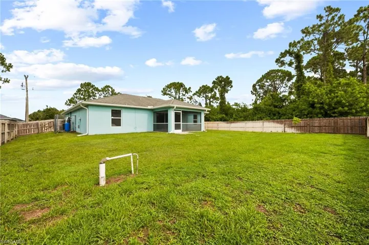 Back of property with a fenced backyard, a sunroom, and stucco siding
