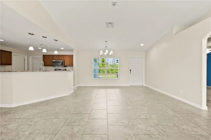 Unfurnished living room featuring recessed lighting, a chandelier, arched walkways, and light tile patterned floors