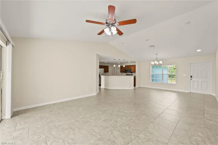 Unfurnished living room featuring a chandelier, lofted ceiling, and a ceiling fan