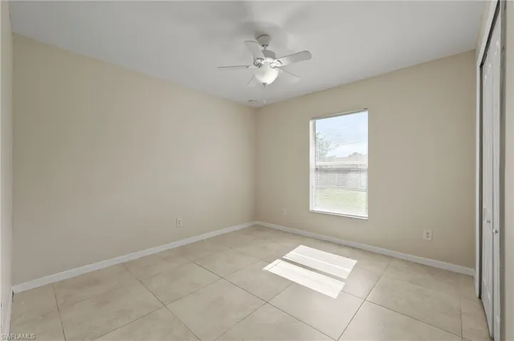 Empty room with light tile patterned flooring and a ceiling fan