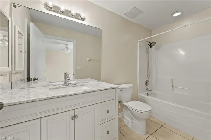 Full bath with tile patterned flooring, vanity, tub / shower combination, and ceiling fan