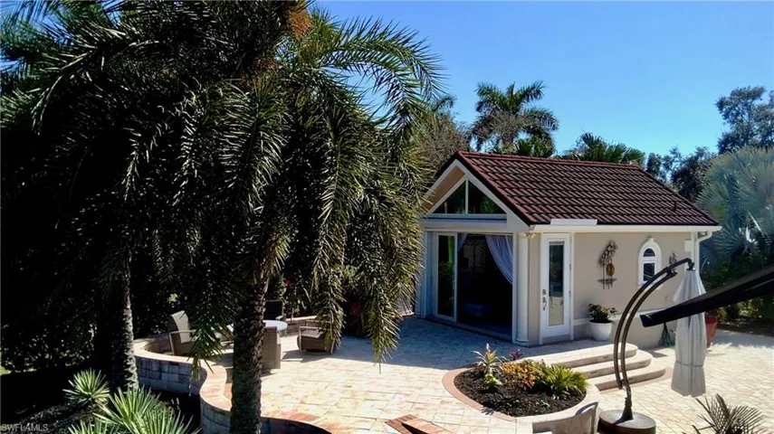 Rear view of property featuring an outdoor structure, a patio area, stucco siding, a tiled roof, and an exterior structure