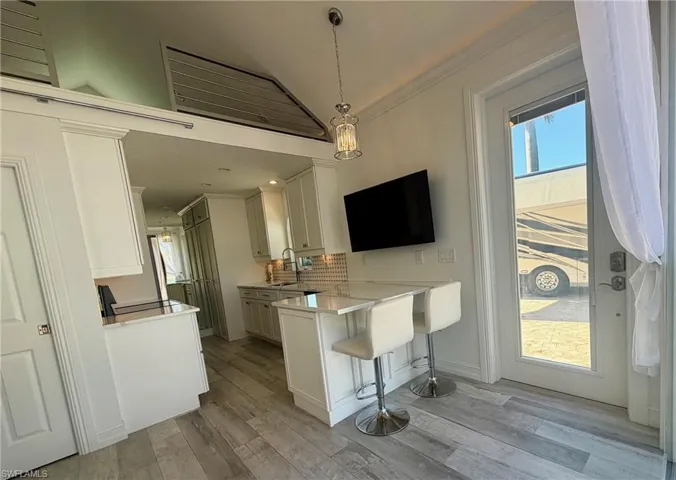 Kitchen with a breakfast bar, a peninsula, healthy amount of natural light, decorative light fixtures, and ornamental molding