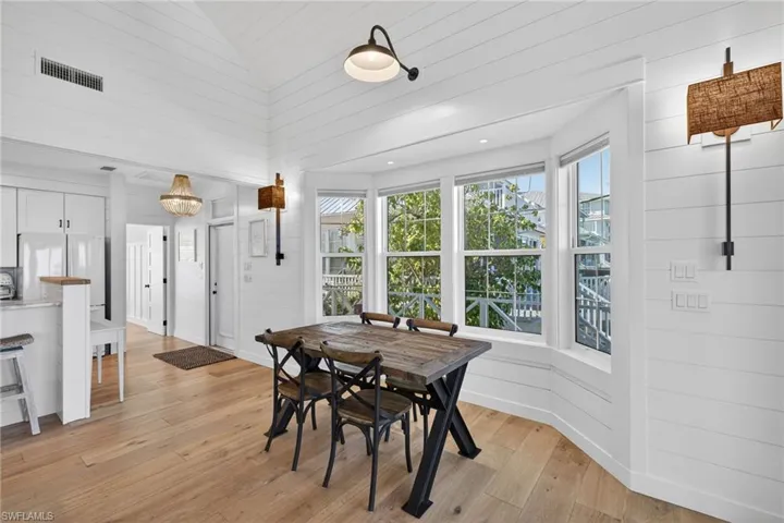 Dining space featuring wood walls, light wood finished floors, healthy amount of natural light, and vaulted ceiling