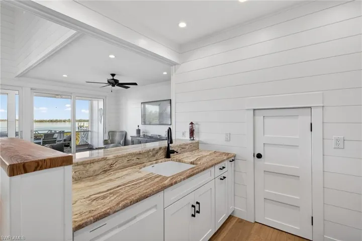 Kitchen featuring white cabinetry, light stone countertops, a water view, recessed lighting, and ceiling fan